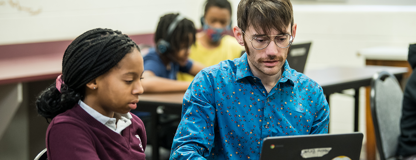 student and a teacher in a classroom with a laptop