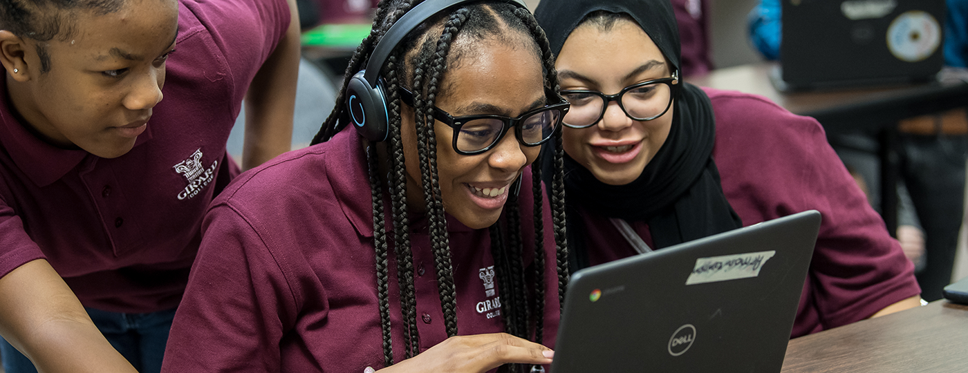 students in a class looking at a laptop smiling