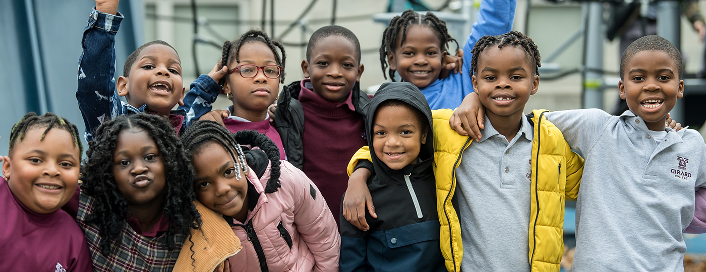 younger students standing and smiling at the camera