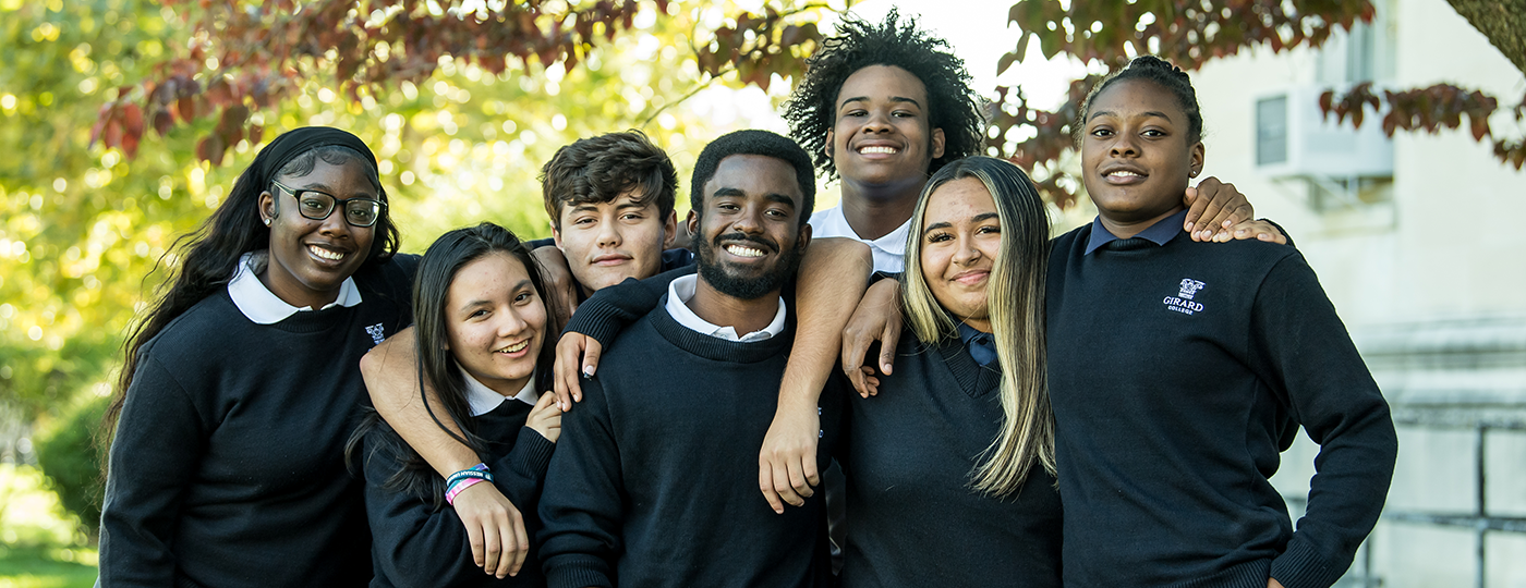 students standing smiling at the camera in their school uniforms