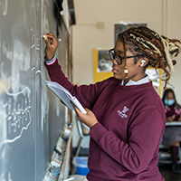 student writing on a blackboard