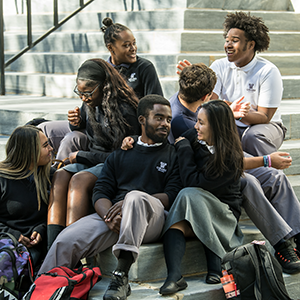 students sitting on campus stairs talking and laughing