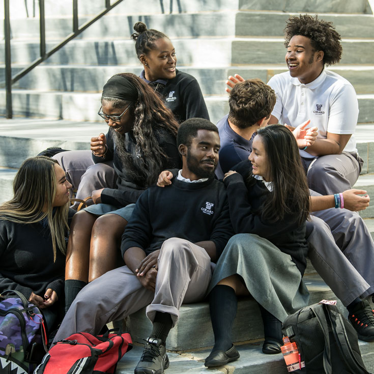 students sitting on campus stairs talking and laughing